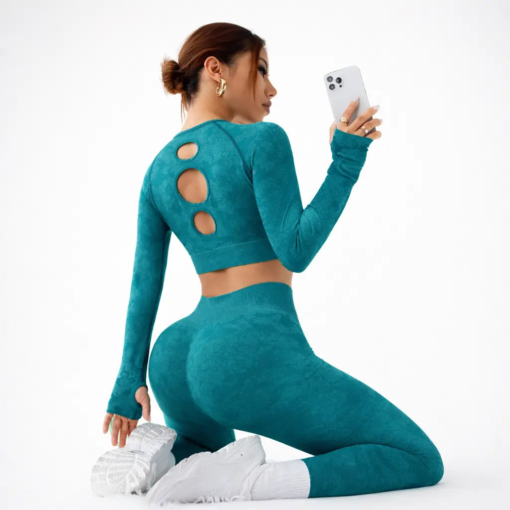 Nylon women's yoga suit for gym and pilates in teal, model wearing long-sleeve crop top with back cutouts and leggings.