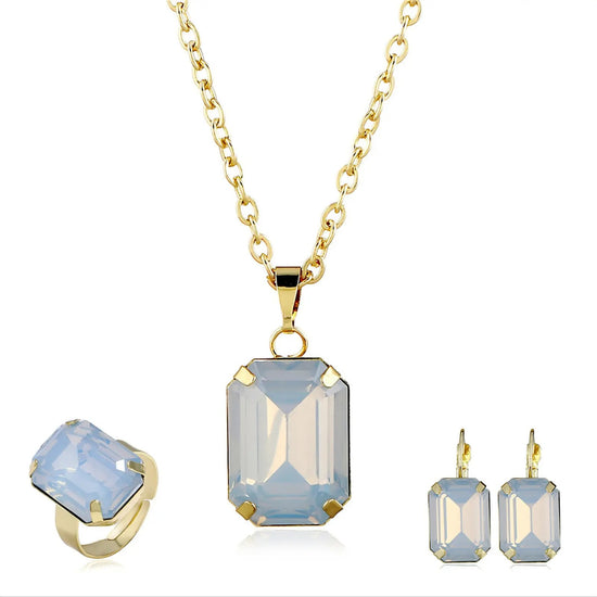 Jewelry set with gold necklace, ring, and earrings featuring blue gemstones on a white background.