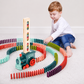 Child playing with a colorful domino train set on a light-colored floor.