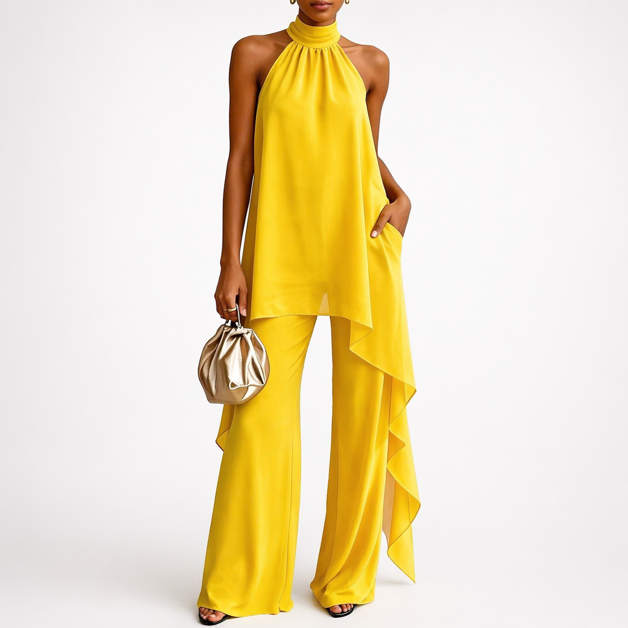 Woman wearing a yellow jumpsuit holding a gold handbag on a white background