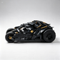 A detailed LEGO Batman Batcave vehicle model in side profile, showcasing its intricate black and gray brick construction with gold accents and large rugged tires, set against a clean light gray studio background.