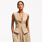 Woman wearing a beige sleeveless blazer and pants on a white background