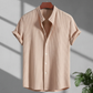 Beige short-sleeve shirt on a hanger with a plant in the corner