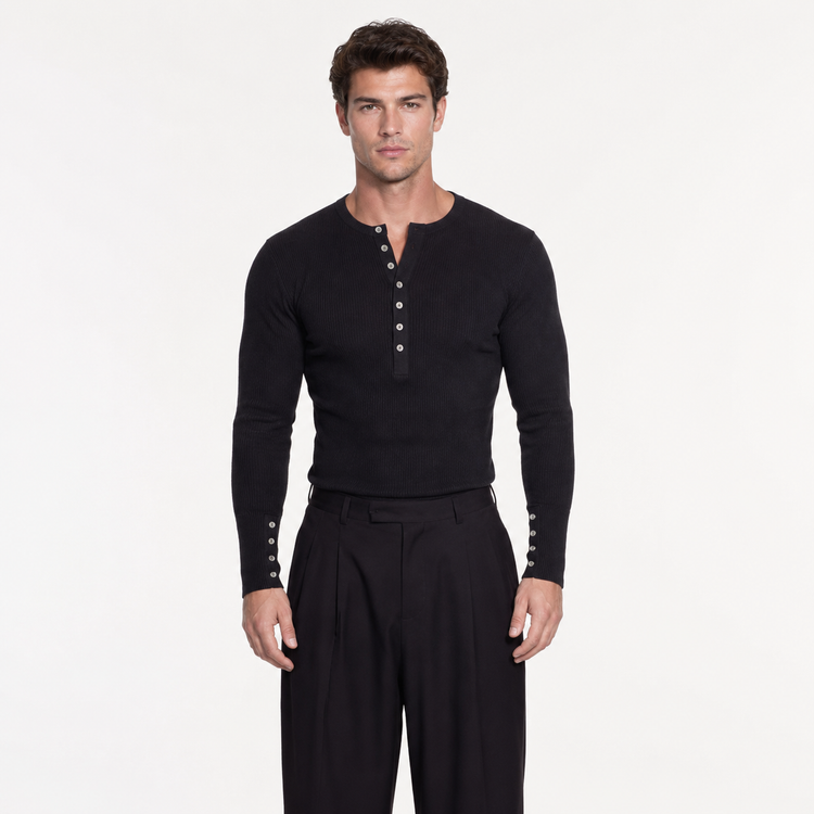 Man wearing a black long-sleeve shirt with buttons and black pants on a white background