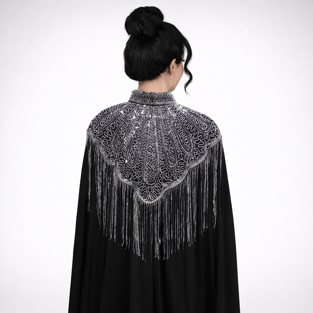 Black cape with intricate silver embroidery and fringe on a white background