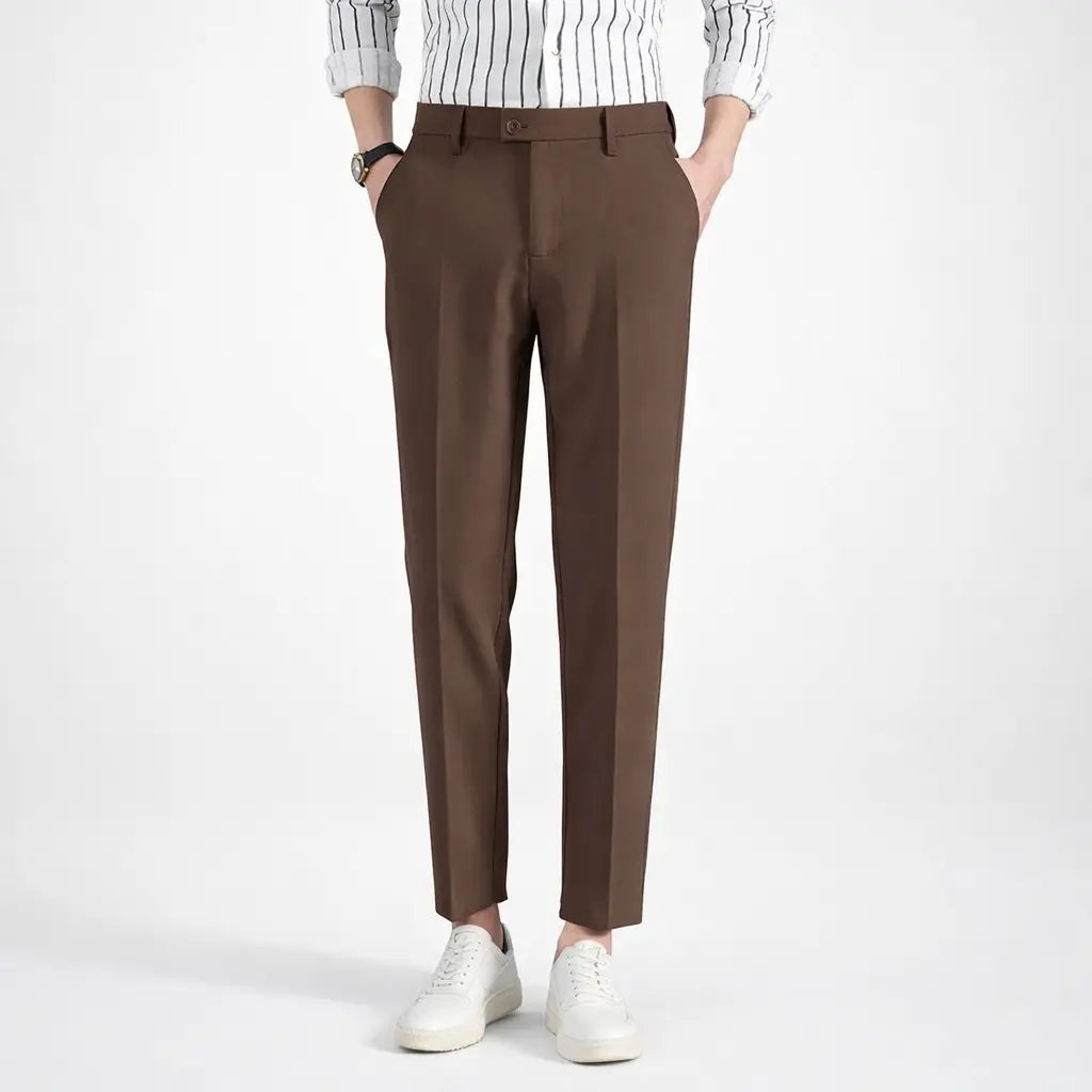 Brown pants worn with a white shirt and white sneakers on a white background