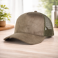 Brown suede cap with green mesh back on a wooden surface