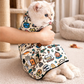 Cat wearing a colorful patterned cone-shaped pet recovery collar, held by a person.