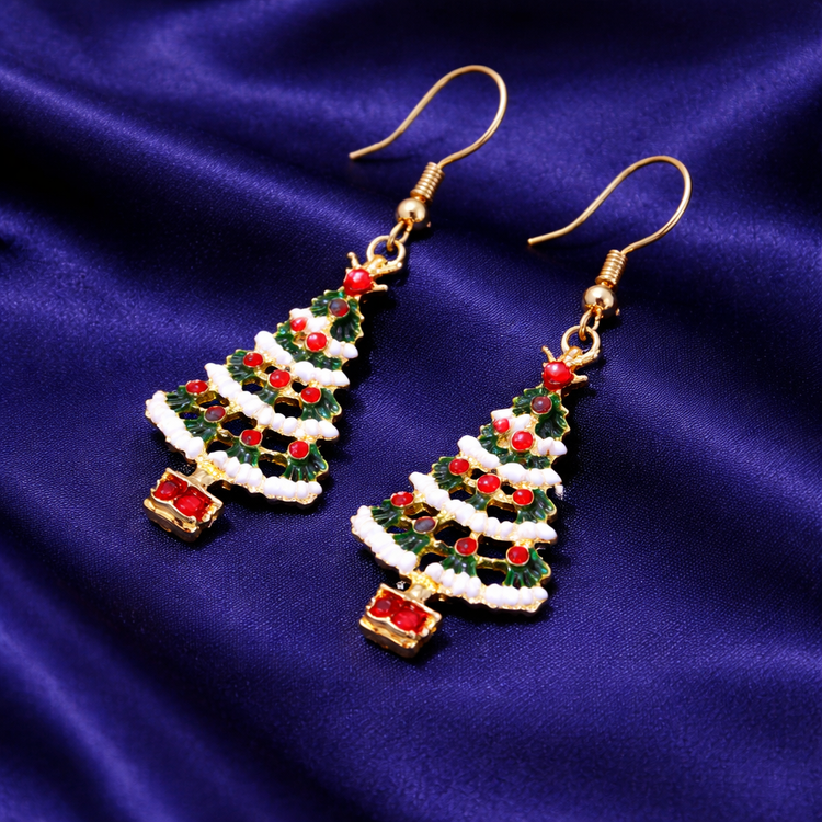 Christmas tree-shaped earrings with red berries on a blue fabric background