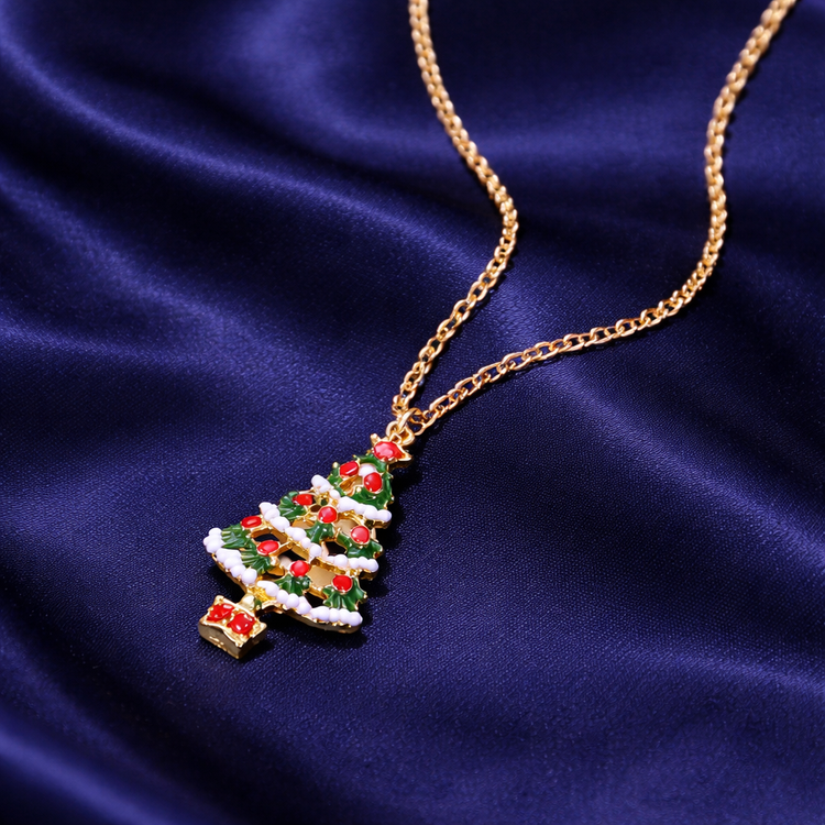 Christmas tree-shaped pendant on a gold chain against a blue fabric background