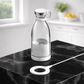Clear glass bottle with white cap and base on a black marble surface BLENDER