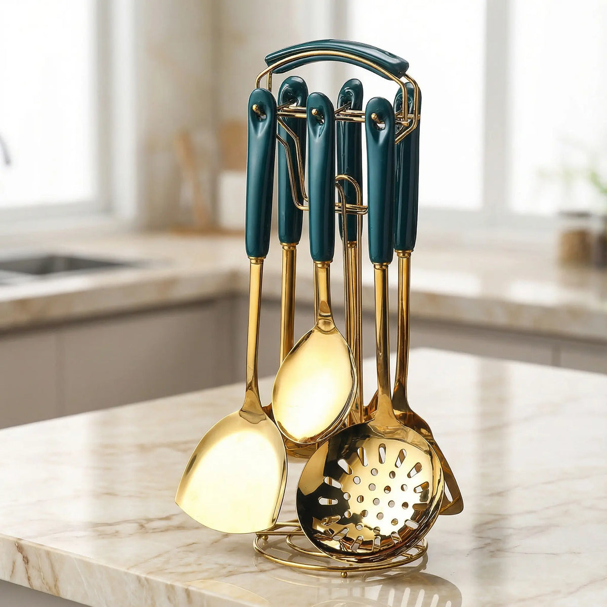 Stainless steel kitchen utensil set with teal handles and gold bodies arranged on a marble countertop.