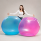 Woman standing between two large inflatable balls, one blue and one pink, on a plain background.