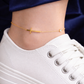 Gold anklet with a cross design on a person&