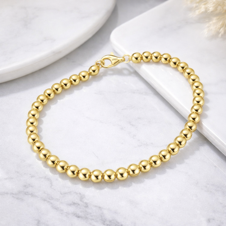 Gold beaded bracelet on a marble surface