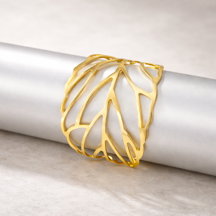 Gold bracelet on a white cylindrical object with a light wooden background