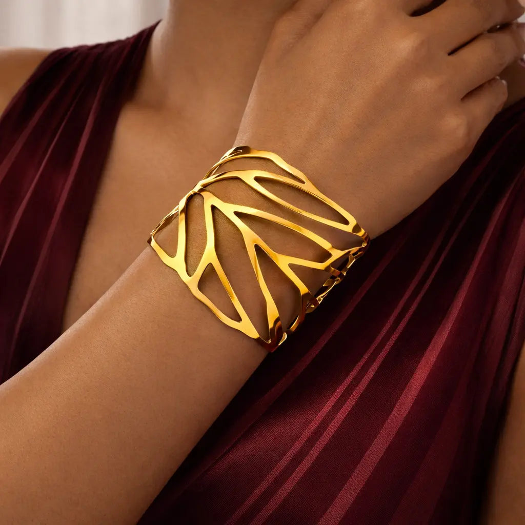 Gold bracelet on a wrist with a maroon fabric background