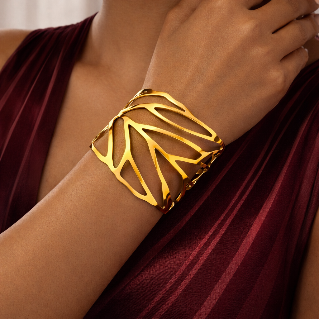 Gold bracelet on a wrist with a maroon fabric background