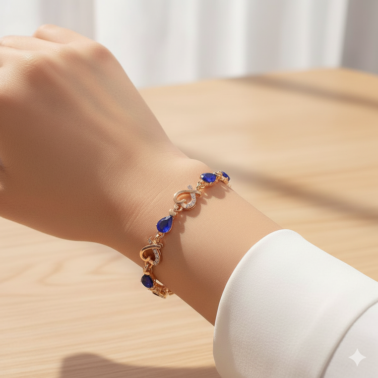 Gold bracelet with blue stones on a wrist against a neutral background