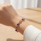 Gold bracelet with blue stones on a wrist against a neutral background