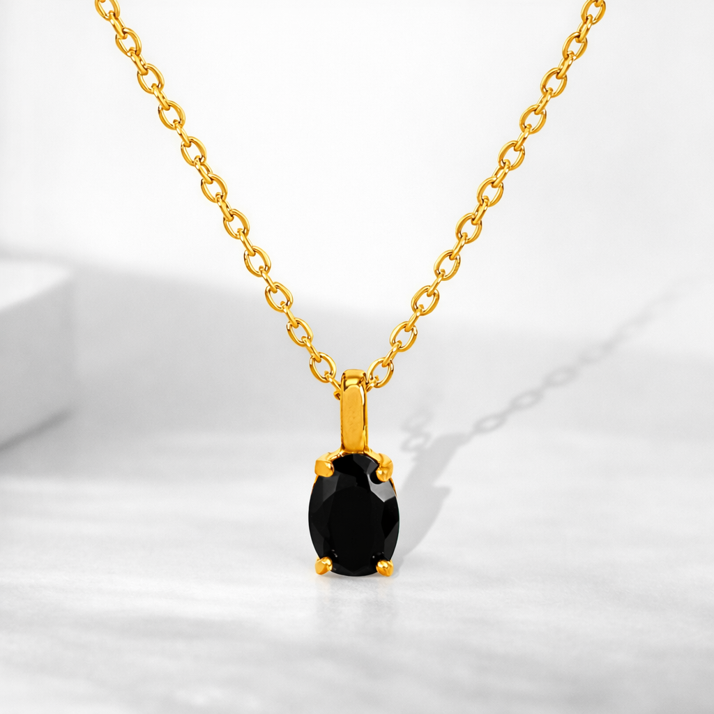 Gold necklace with a black gemstone pendant on a white background
