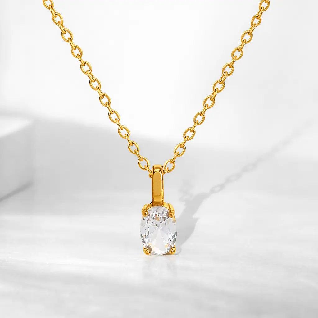 Design necklace with a clear oval pendant set in gold, displayed on a white background