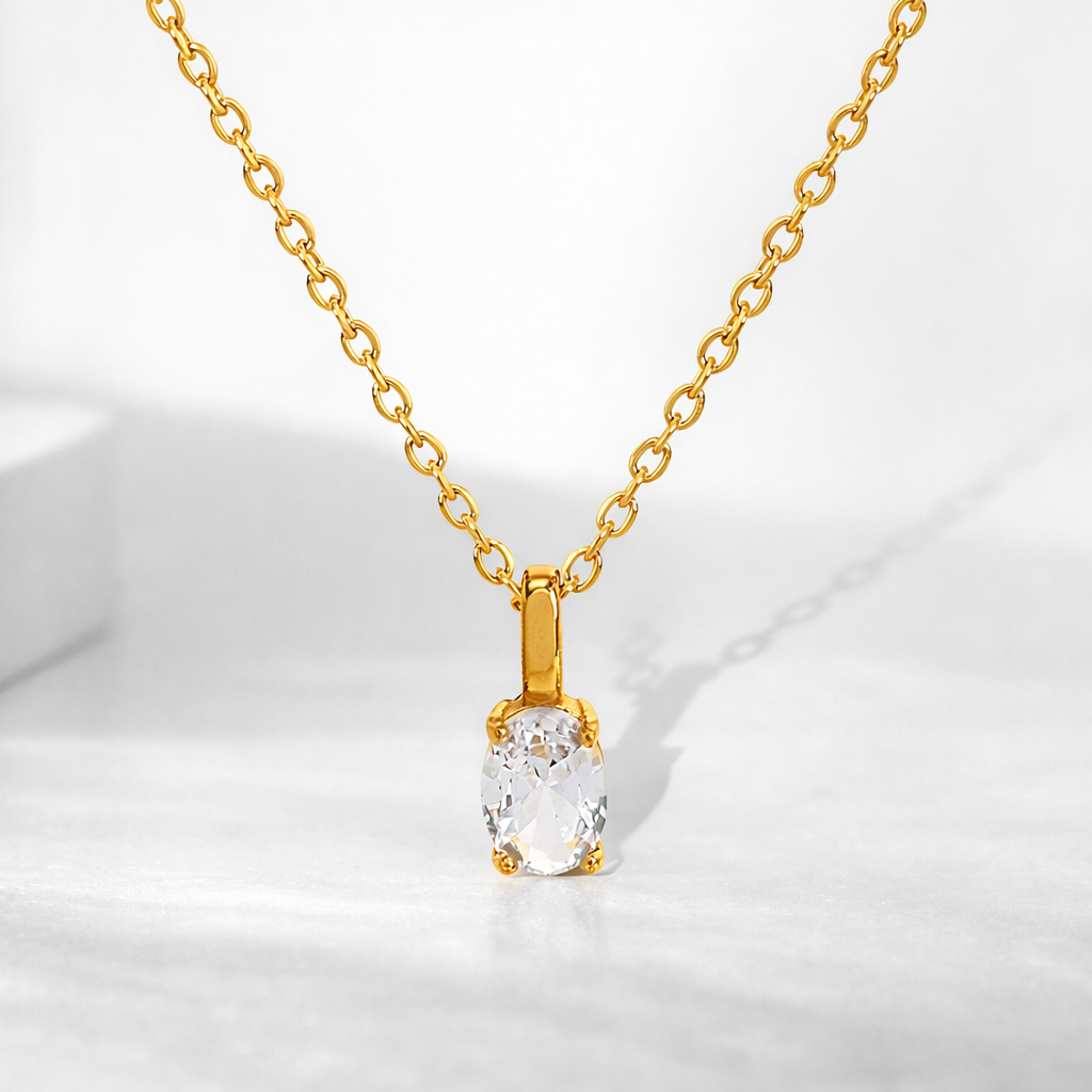 Gold necklace with a clear pendant on a white background