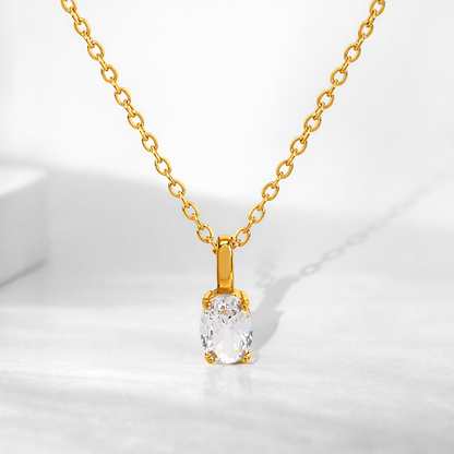 Gold necklace with a clear pendant on a white background