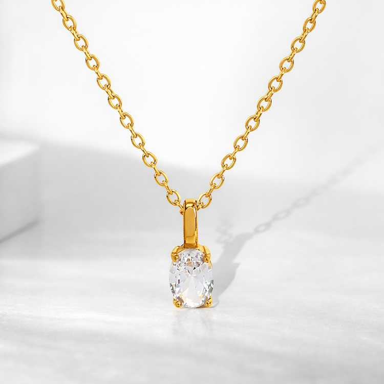 Gold necklace with a clear pendant on a white background