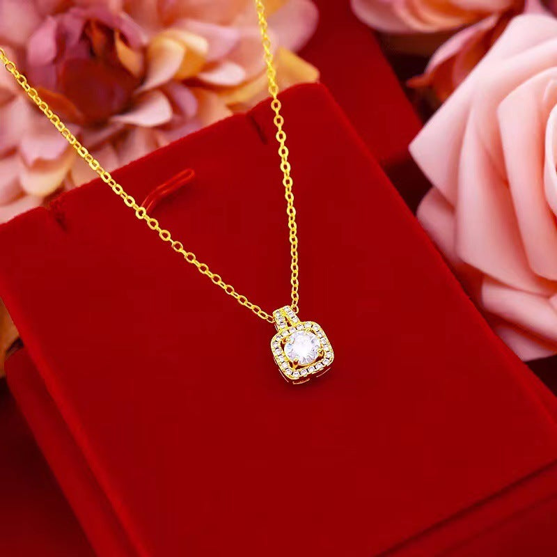 Gold necklace with a diamond pendant on a red velvet surface with flowers in the background