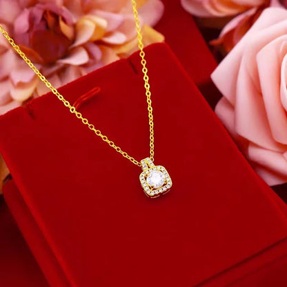 Gold necklace with a diamond pendant on a red velvet surface with flowers in the background