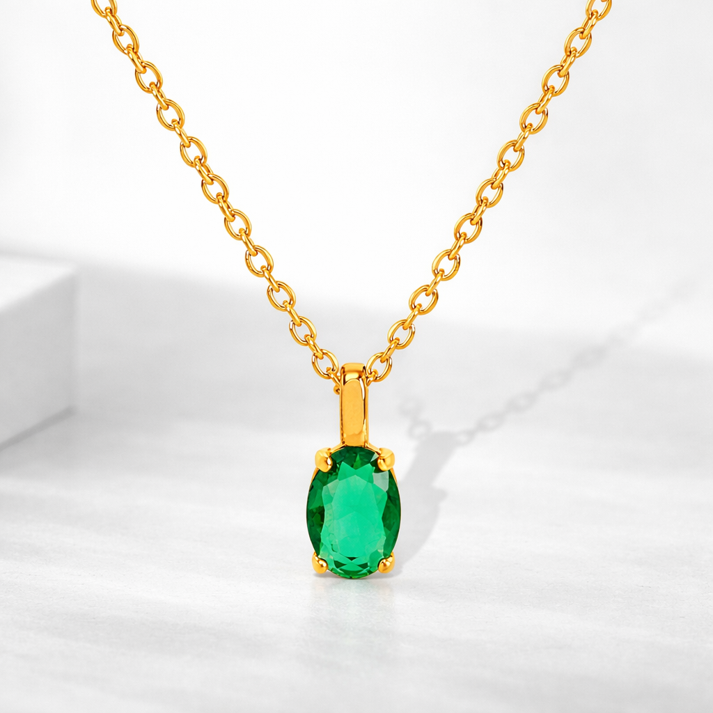 Gold necklace with a green gemstone pendant on a white background
