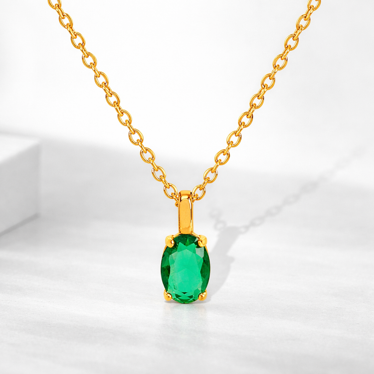 Gold necklace with a green gemstone pendant on a white background