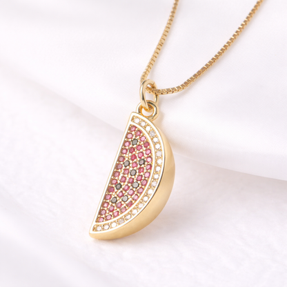 Gold necklace with a pink gemstone pendant on a white background
