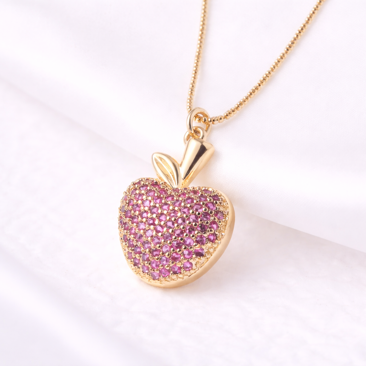 Gold necklace with a pink heart-shaped pendant on a white background