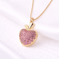 Gold necklace with a pink heart-shaped pendant on a white background