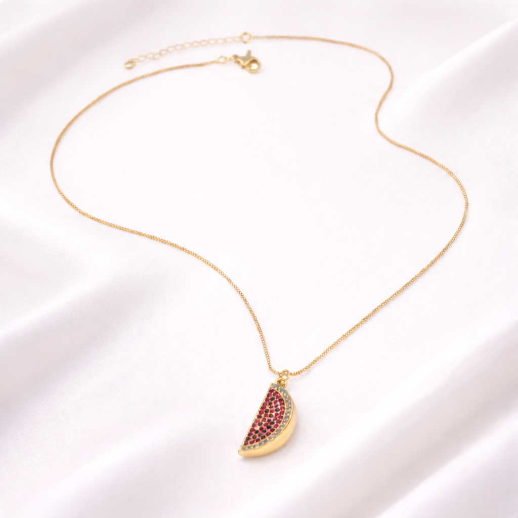 Gold necklace with a watermelon slice pendant on a white background