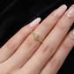 Gold ring on a hand with decorative nails against a black background