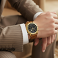 Gold wristwatch on a person wearing a suit with a blurred background