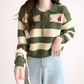 Green and beige striped sweater with a floral detail on a plain background