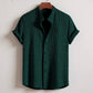 Green textured shirt on a hanger against a white background