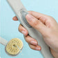 Hand holding a kitchen cleaning tool with a sponge attachment against a light blue background