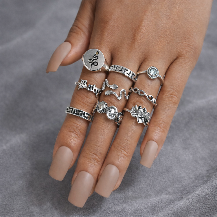 Hand wearing multiple silver rings on a gray background