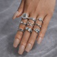 Hand wearing multiple silver rings on a gray background