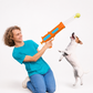 Person playing with a dog using a toy gun on a white background