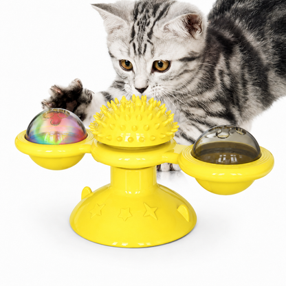 Cat playing with a yellow rotating toy on a white background