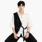 Man wearing a white shirt with a black vest and pants on a white background