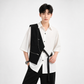 Person wearing a black and white outfit with a vest on a white background