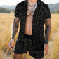 Man wearing a black patterned shirt and shorts in a field