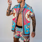 Man wearing a colorful patterned shirt and shorts on a plain background